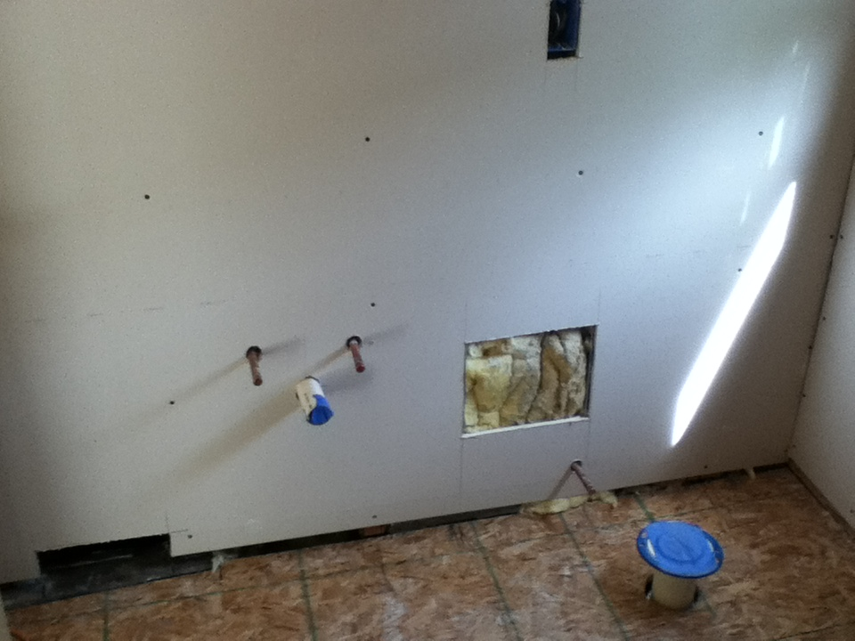 Vanity area with new drywall installed. Vanity plumbing, stool plumbing, laundry shoot, and toe kick heat cut out from drywall.