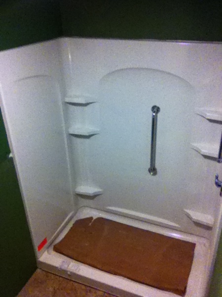 Walk-in shower stall installed with moisture resistant drywall surrounding the shower unit.