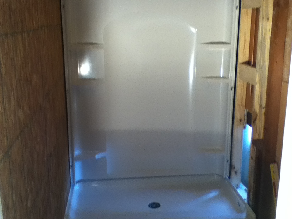 Walk-in shower stall during installation. Shower base and back wall unit currently installed.