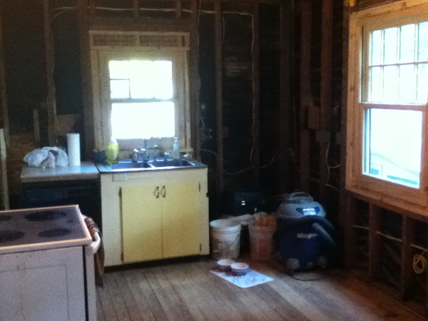 Kitchen demoed to bare studs, sink remains hooked up. New windows installed.